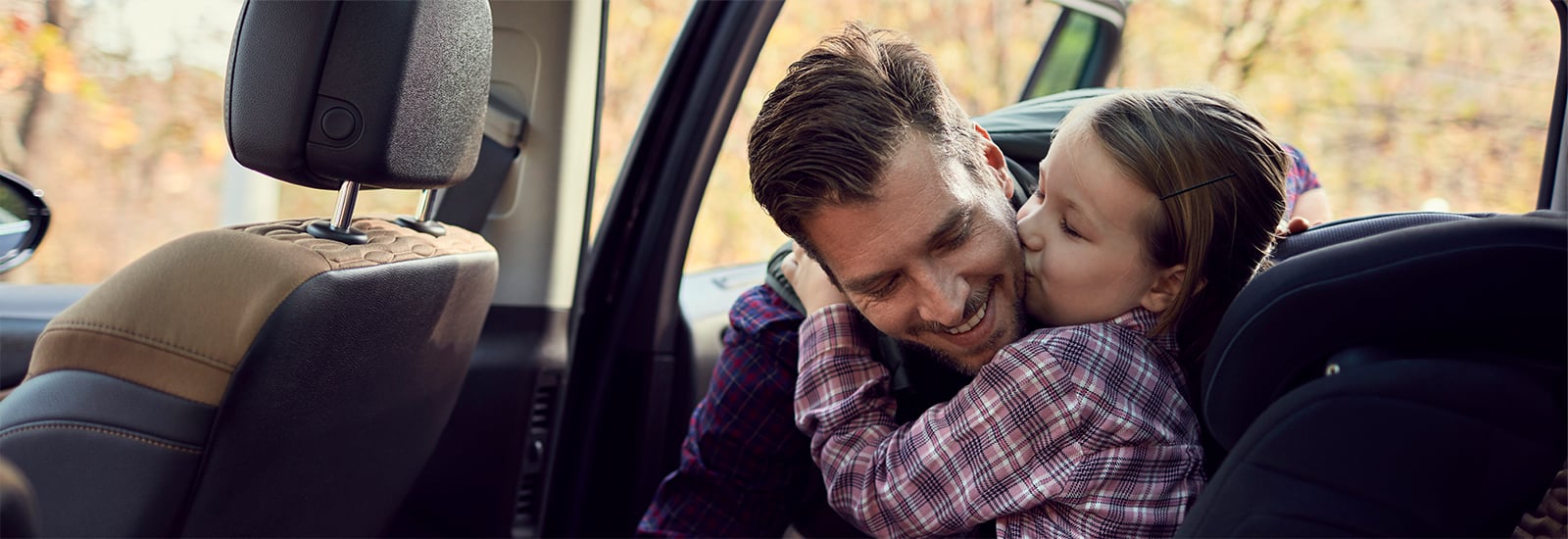 father hugging child sitting in a car seat