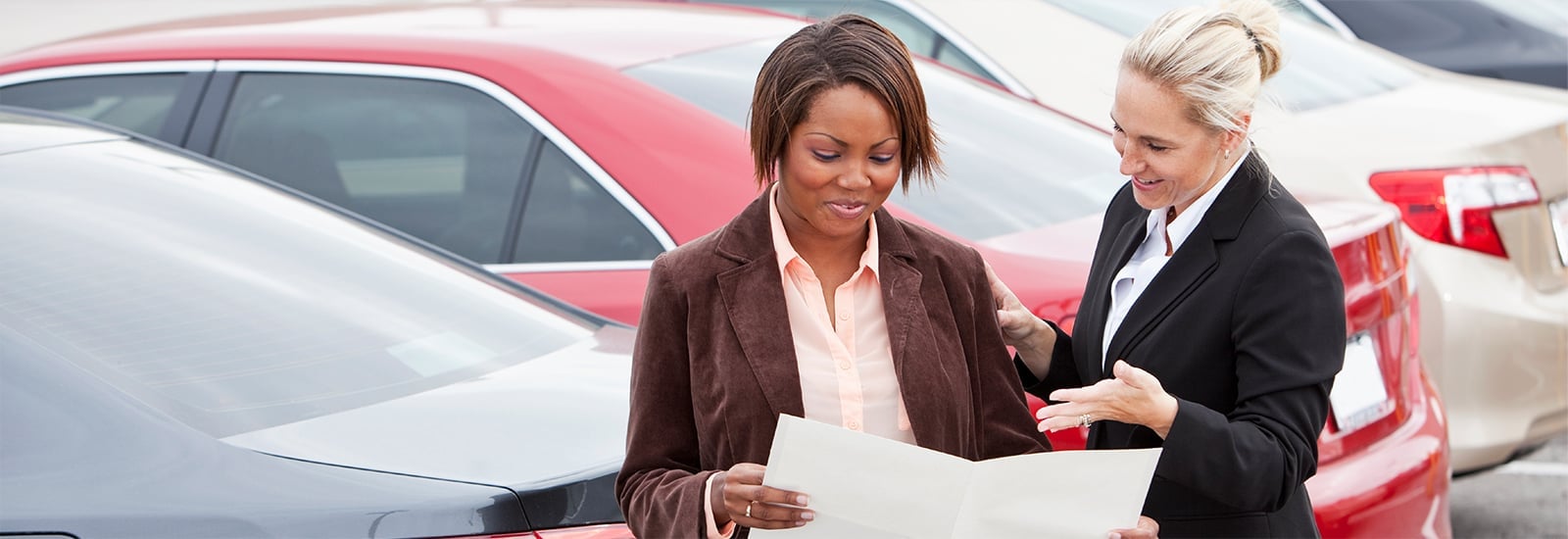 Two women standing in front of cars