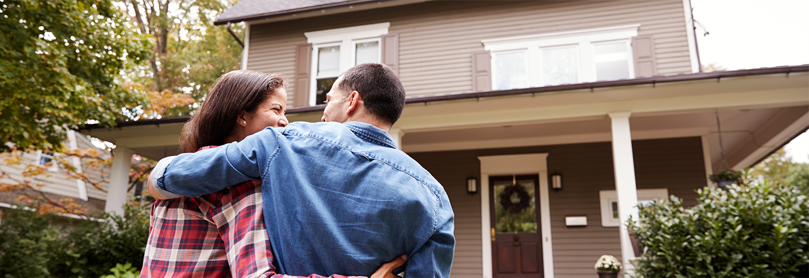 couple embracing while looking at their home