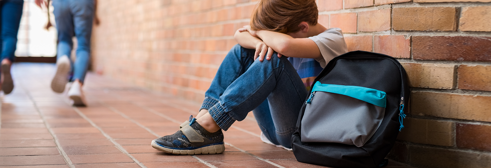 Child sitting on the ground with his head down