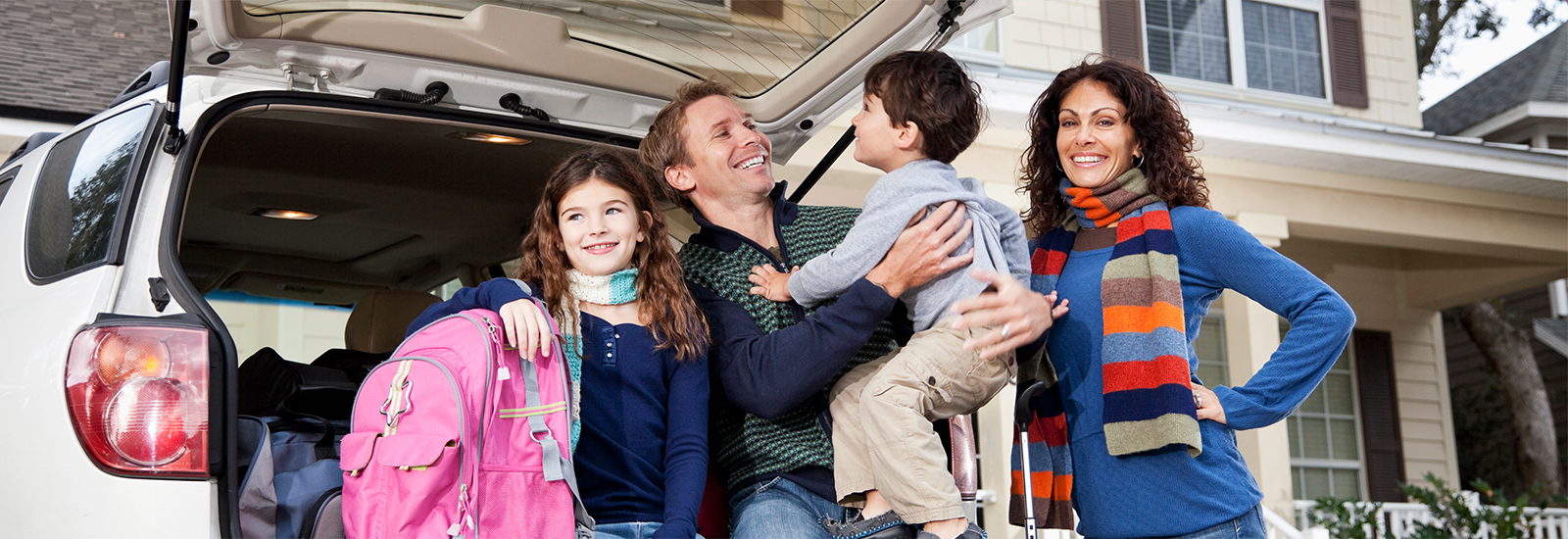 family standing outside in front of a car