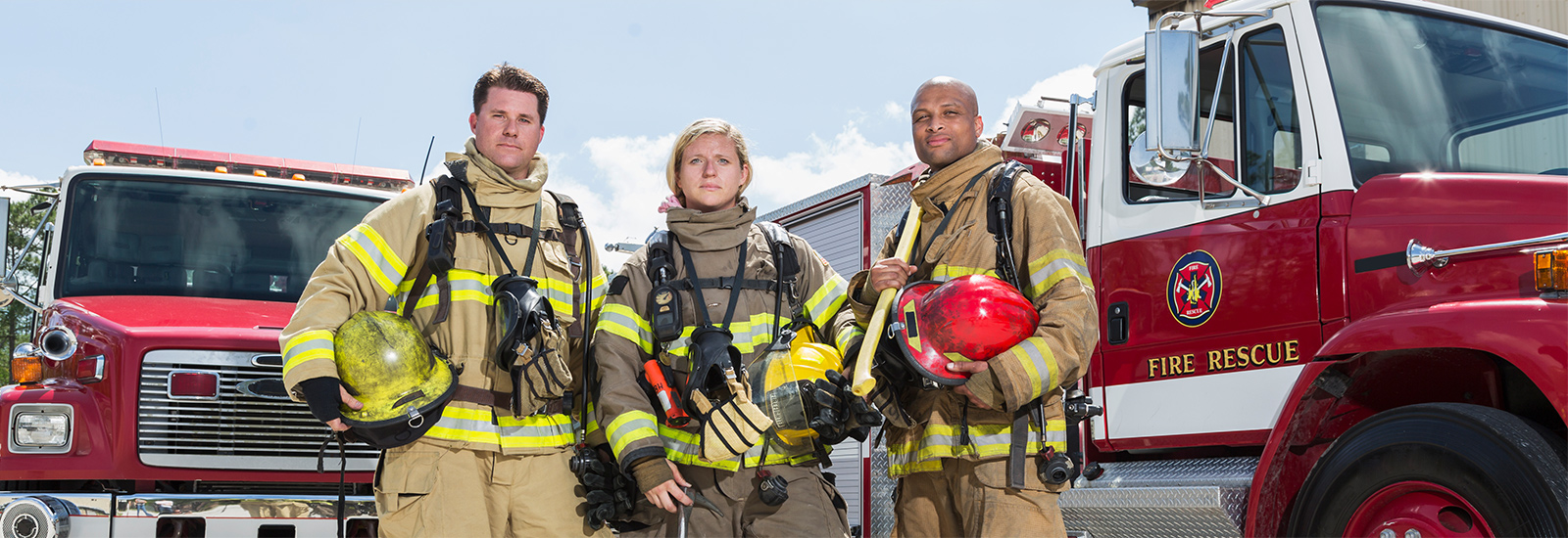 Group of Fire Fighters standing in front of fire trucks